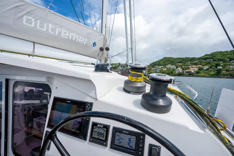 Inky Blue Yacht Photos Pics 2020 Outremer 51 yacht cockpit with navigation instruments and winches, overlooking coastal scenery.