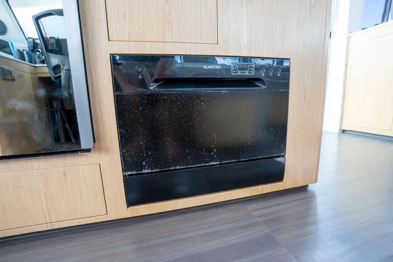 Inky Blue Yacht Photos Pics Built-in dishwasher on 2020 Outremer 51 yacht, featuring sleek black design and wooden cabinetry.