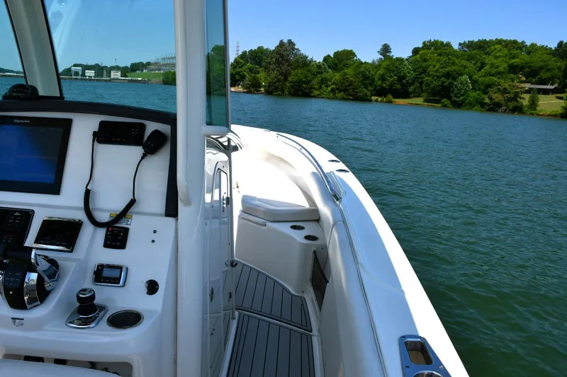  Yacht Photos Pics 2016 Boston Whaler 280 Outrage boat on a serene lake with lush green shoreline.