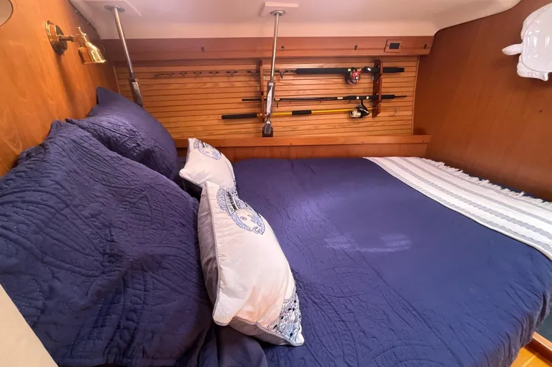 Spellbound Yacht Photos Pics Cozy cabin interior of 2000 Catalina 470 yacht with blue bedding and fishing rods.