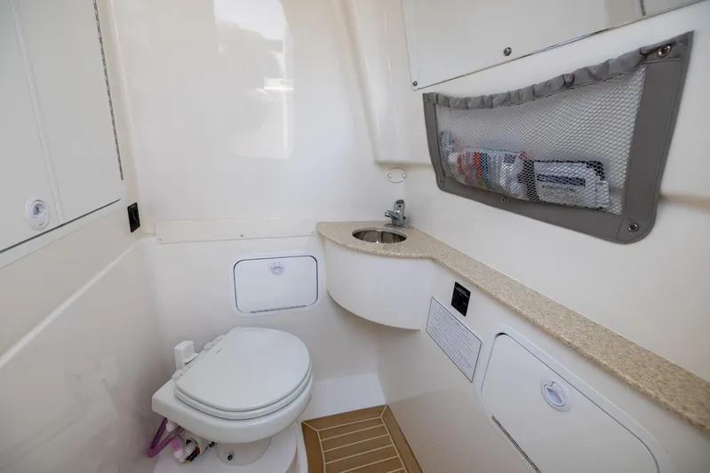 Big D Yacht Photos Pics 2021 Regulator 28FS boat bathroom with sink, toilet, and storage compartments.