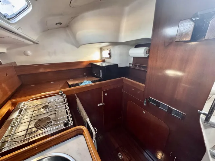  Yacht Photos Pics Interior of 1991 Beneteau 45 First yacht kitchen with stove and wooden cabinetry.