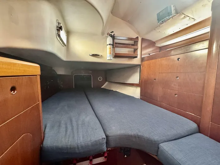  Yacht Photos Pics Interior cabin of 1991 Beneteau 45 First sailboat with wooden cabinetry and blue cushions.