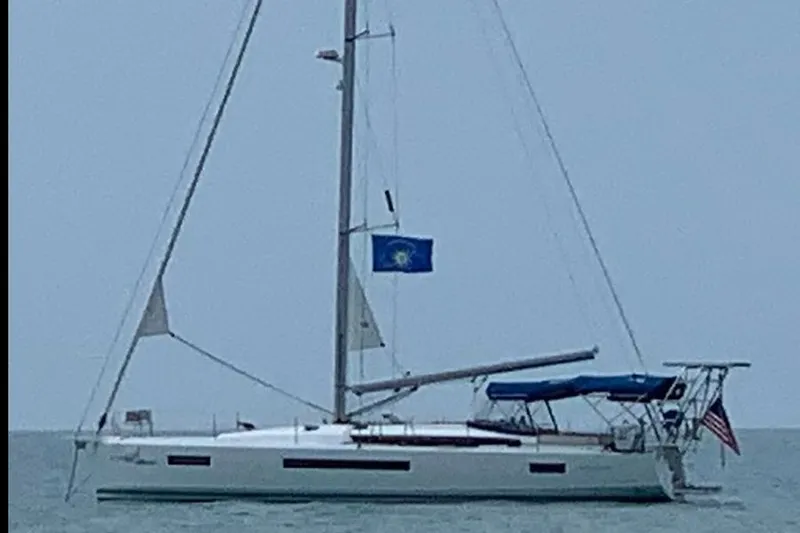 Nautical Dreamer Yacht Photos Pics 2019 Jeanneau Sun Odyssey 490 sailboat on calm waters with flags.