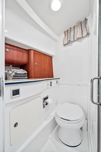 Pura Vita Yacht Photos Pics 2006 Intrepid 377 WA boat bathroom with toilet, sink, and wooden cabinetry.