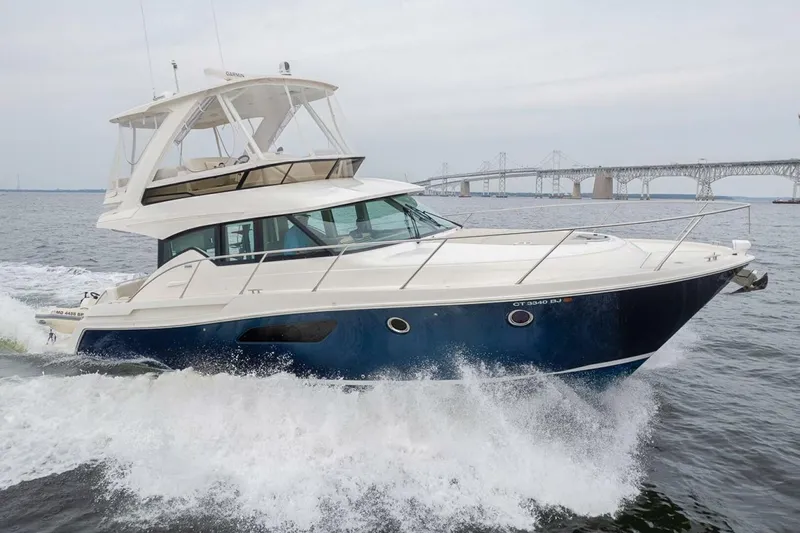  Yacht Photos Pics 2021 Tiara Yachts F44 Flybridge cruising on water near a bridge.