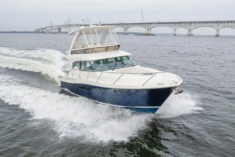  Yacht Photos Pics 2021 Tiara Yachts F44 Flybridge cruising near a bridge on open water.