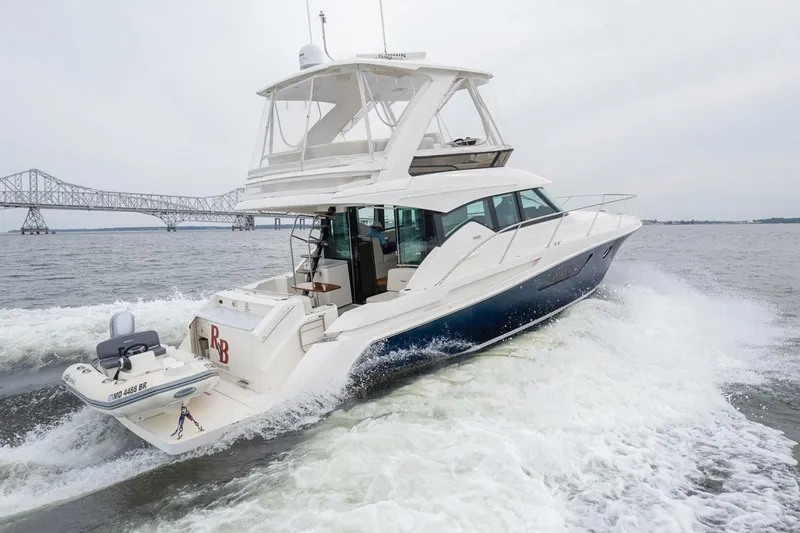  Yacht Photos Pics 2021 Tiara Yachts F44 Flybridge cruising near a bridge on open water.