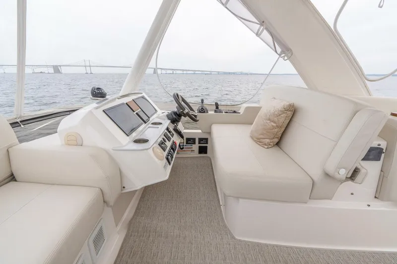  Yacht Photos Pics 2021 Tiara Yachts F44 Flybridge interior with helm and seating, overlooking water and bridge.