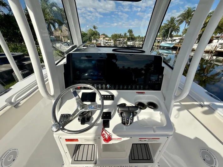  Yacht Photos Pics 2024 Sea Hunt Ultra 275 SE helm with steering wheel and control panel, docked by palm trees.