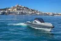 2008 SACS Strider boat cruising near a coastal city with a historic hilltop view.