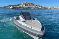 2008 SACS Strider boat cruising near a coastal city with a lighthouse and hilltop buildings.