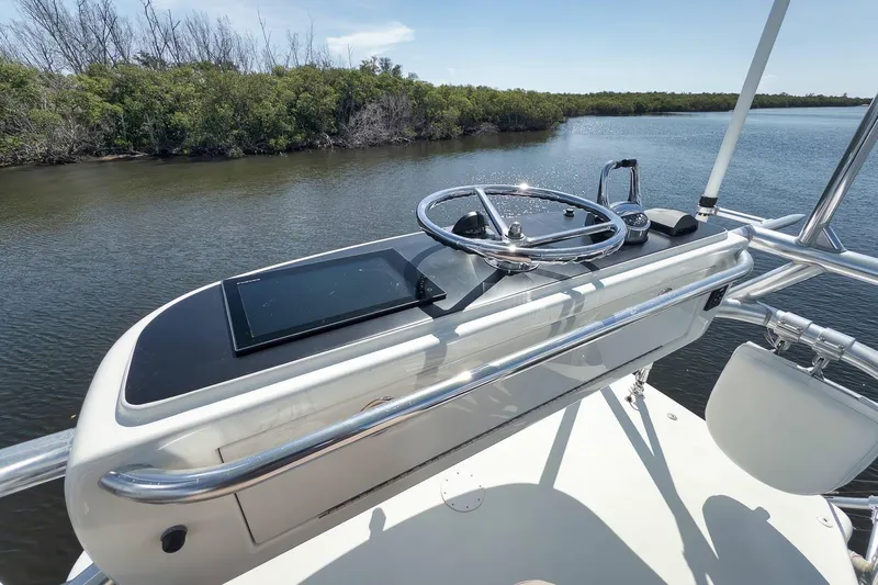 Sparkle Plenty Yacht Photos Pics 2009 Gamefisherman Express boat helm with steering wheel and navigation panel, near lush shoreline.