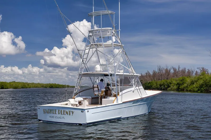 Sparkle Plenty Yacht Photos Pics 2009 Gamefisherman Express boat on water, clear sky, lush greenery in background.