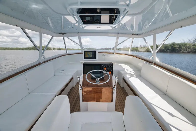 Sparkle Plenty Yacht Photos Pics 2009 Gamefisherman Express boat interior with white seating and wooden helm, on calm water.