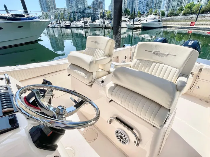  Yacht Photos Pics 2014 Grady-White Canyon 306 boat interior with steering wheel and cushioned seats in a marina.