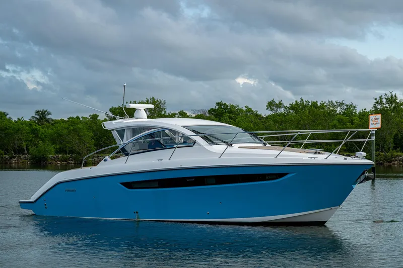  Yacht Photos Pics 2018 Pursuit SC 365i Sport Coupe yacht on calm water, surrounded by greenery.