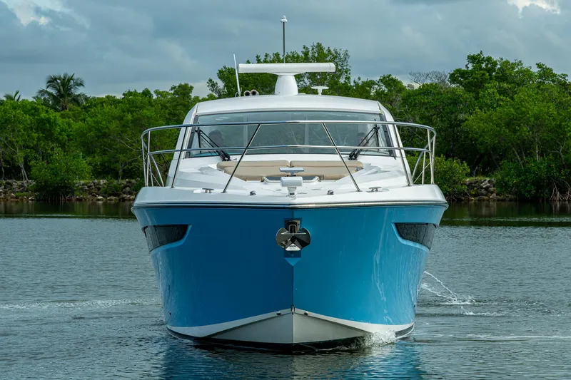  Yacht Photos Pics 2018 Pursuit SC 365i Sport Coupe yacht on calm water, surrounded by lush greenery.