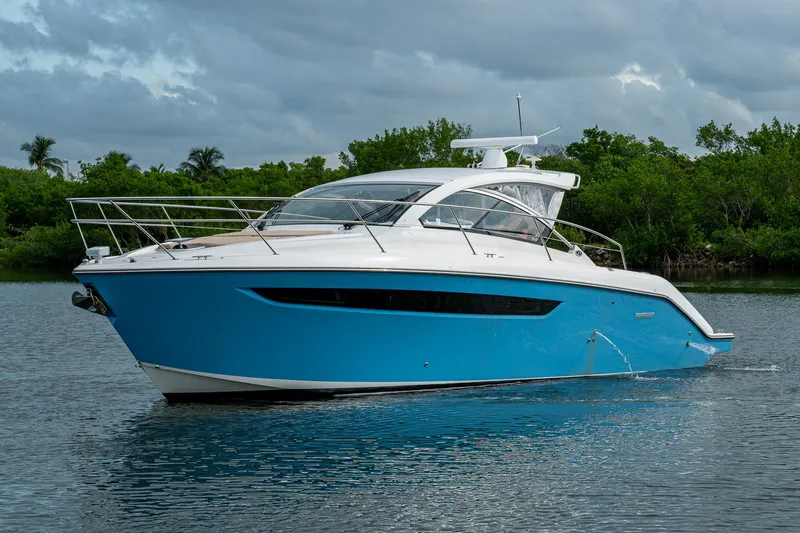  Yacht Photos Pics 2018 Pursuit SC 365i Sport Coupe yacht on calm water, surrounded by lush greenery.