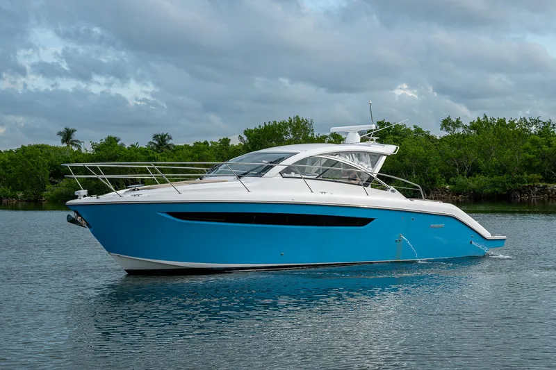  Yacht Photos Pics 2018 Pursuit SC 365i Sport Coupe yacht on calm water, surrounded by lush greenery.