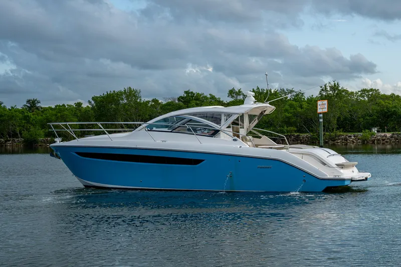  Yacht Photos Pics 2018 Pursuit SC 365i Sport Coupe yacht on calm water, surrounded by lush greenery.