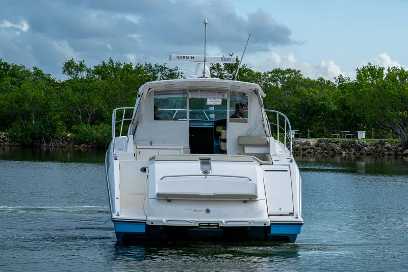  Yacht Photos Pics 2018 Pursuit SC 365i Sport Coupe cruising on a calm waterway, surrounded by lush greenery.