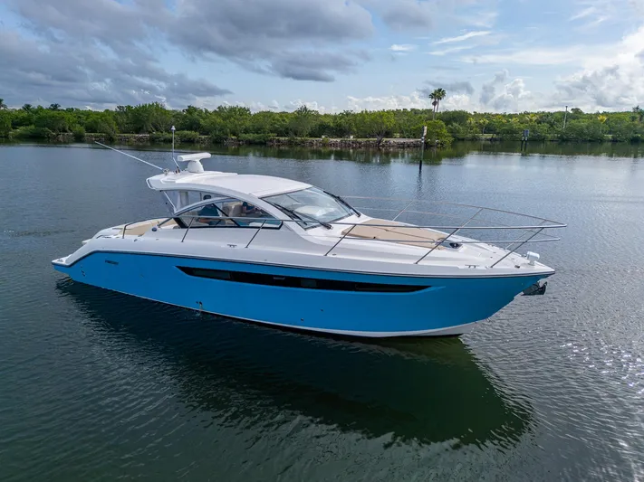  Yacht Photos Pics 2018 Pursuit SC 365i Sport Coupe cruising on calm waters under a cloudy sky.