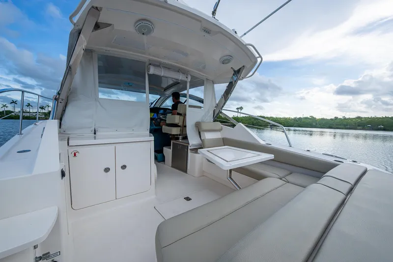  Yacht Photos Pics 2018 Pursuit SC 365i Sport Coupe interior with seating and table, overlooking serene water.