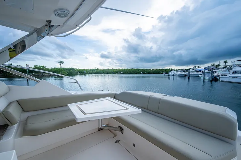  Yacht Photos Pics 2018 Pursuit SC 365i Sport Coupe interior with waterfront view, featuring comfortable seating and table.