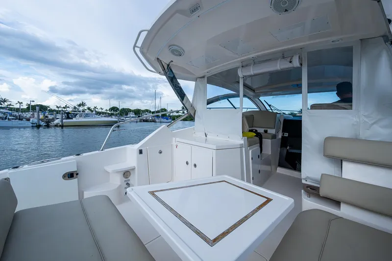  Yacht Photos Pics 2018 Pursuit SC 365i Sport Coupe interior with seating and table, docked at marina.