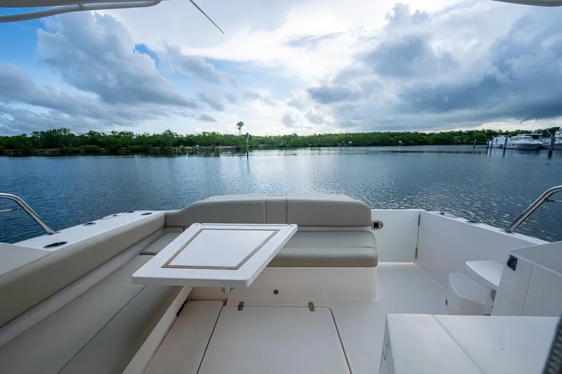  Yacht Photos Pics 2018 Pursuit SC 365i Sport Coupe boat interior with seating and table, overlooking calm waters.