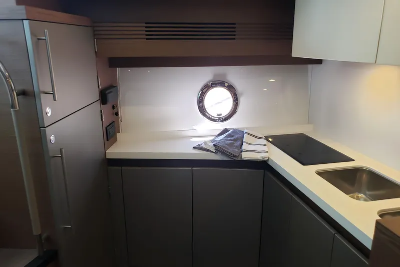 Tu Madre Yacht Photos Pics Modern kitchen interior of 2019 Beneteau Gran Turismo 46 yacht with sleek cabinetry and porthole.