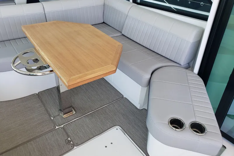 Tu Madre Yacht Photos Pics 2019 Beneteau Gran Turismo 46 interior with gray seating, wooden table, and cup holders.