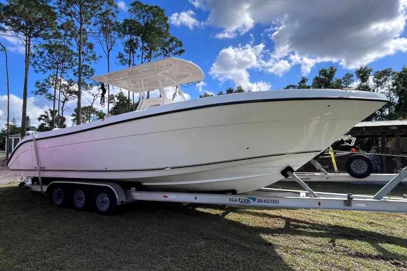  Yacht Photos Pics 2019 Century 3200 Center Console boat on trailer, surrounded by trees and blue sky.
