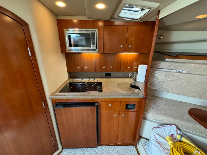  Yacht Photos Pics 2011 Rampage 34 IPS yacht interior with kitchenette, featuring wood cabinets, stove, microwave, and mini-fridge.