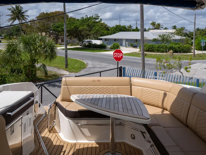 Soiral V Yacht Photos Pics 2021 Sea Ray 320 Sundancer boat with outdoor seating and table, docked near a residential area.