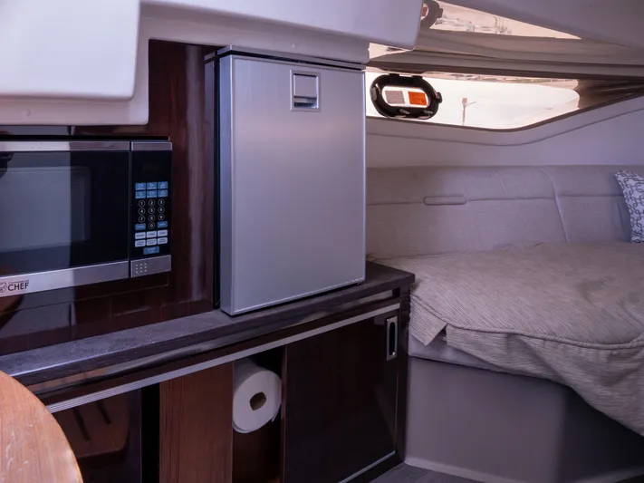 Soiral V Yacht Photos Pics Interior of 2021 Sea Ray 320 Sundancer with kitchenette and cozy sleeping area.