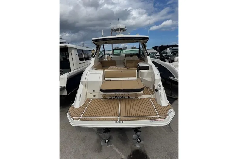 Soiral V Yacht Photos Pics 2021 Sea Ray 320 Sundancer boat with spacious deck and seating, docked under cloudy skies.