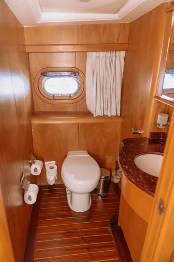  Yacht Photos Pics Wood-paneled bathroom in 2005 custom-made gulet, featuring toilet, sink, and porthole window.