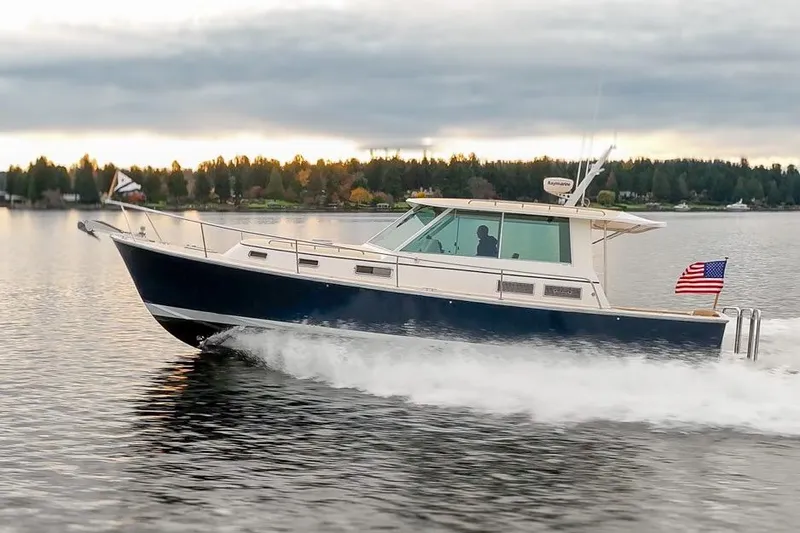 Peddler Yacht Photos Pics 2007 Bruckmann BLUESTAR boat cruising on a serene lake with an American flag.
