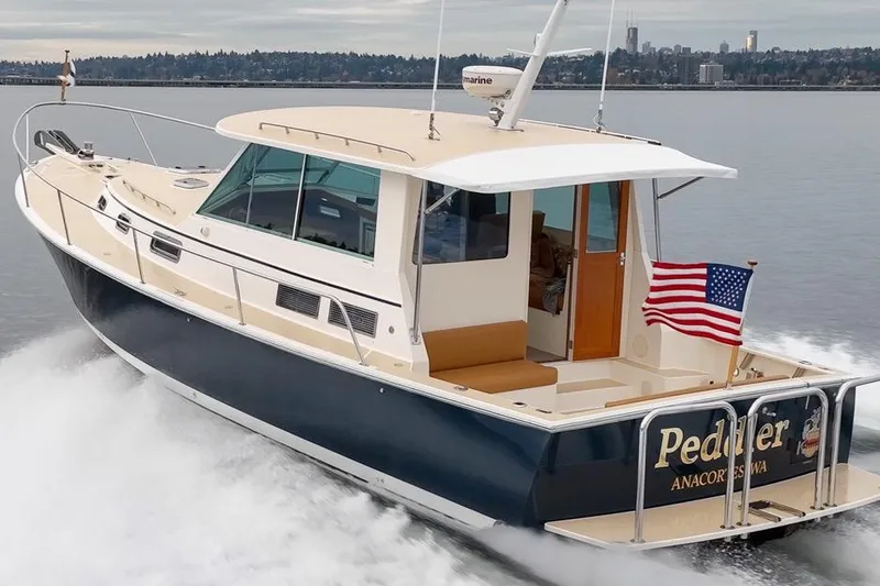 Peddler Yacht Photos Pics 2007 Bruckmann BLUESTAR boat cruising with American flag, scenic waterfront background.