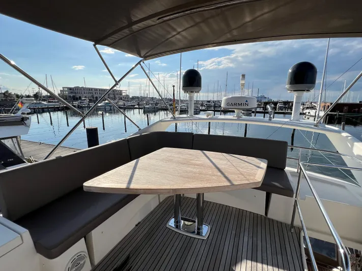 Kuramati III Yacht Photos Pics Flybridge seating area on 2016 Prestige 500 yacht, overlooking marina with clear skies.