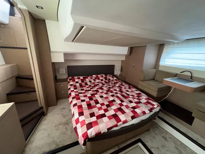 Kuramati III Yacht Photos Pics Luxurious bedroom interior of a 2016 Prestige 500 yacht with a red checkered bedspread.