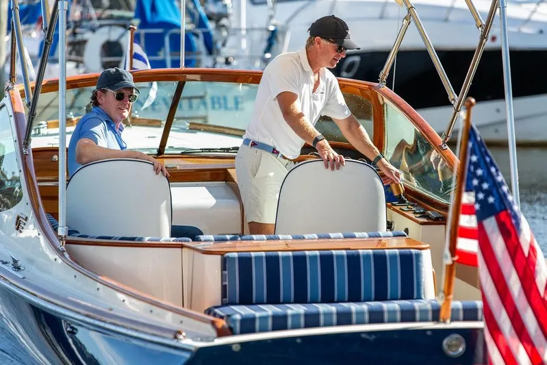 Firefly Yacht Photos Pics Two people on a 2003 Hinckley T29R boat with American flag, docked at marina.