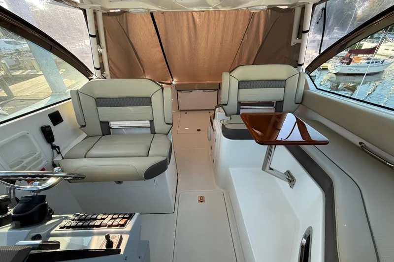  Yacht Photos Pics 2019 Pursuit DC 325 Dual Console interior with seating and wooden table, docked at marina.