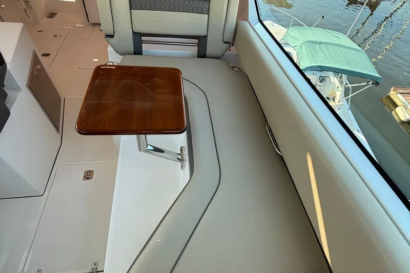  Yacht Photos Pics 2019 Pursuit DC 325 Dual Console interior with wooden table and seating.
