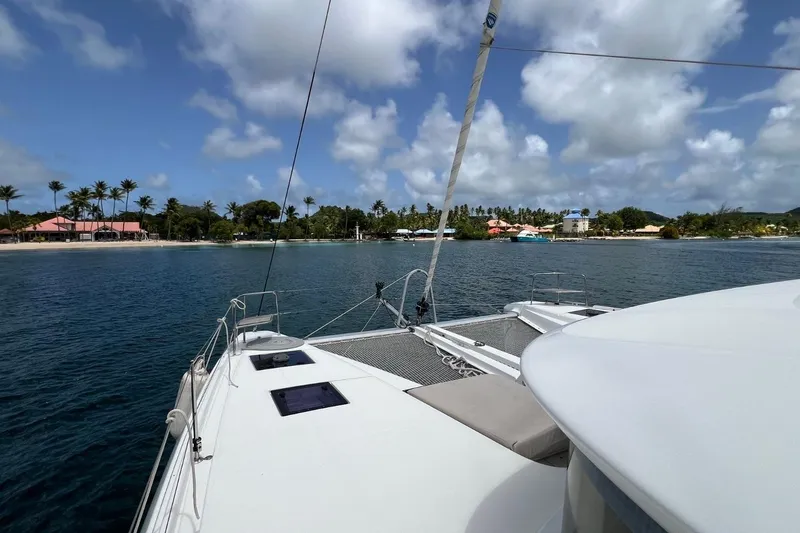 Dignity Yacht Photos Pics Lagoon 50 catamaran sailing near tropical beach, 2021 model, clear skies, palm trees.