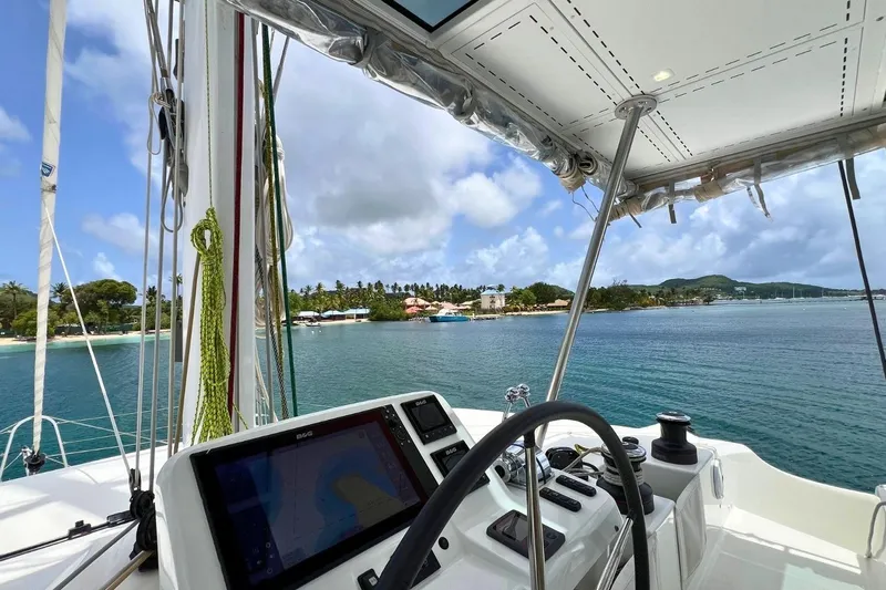 Dignity Yacht Photos Pics Cockpit view from 2021 Lagoon 50 catamaran, overlooking tropical coastline and clear blue waters.
