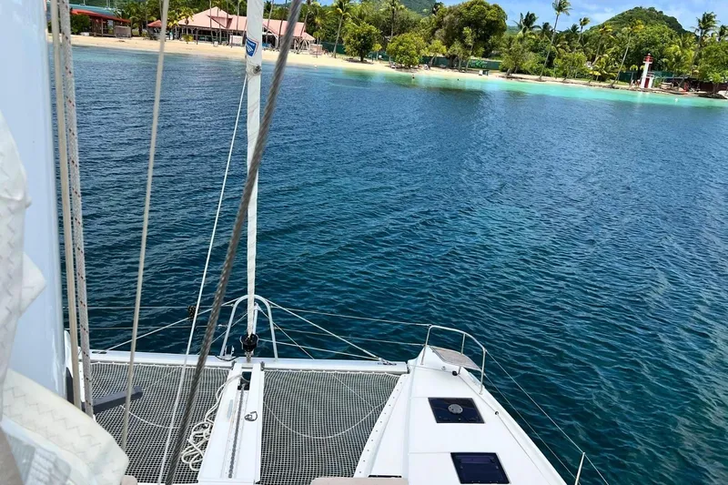 Dignity Yacht Photos Pics Lagoon 50 catamaran sailing near tropical island with lush greenery and sandy beach, 2021 model.