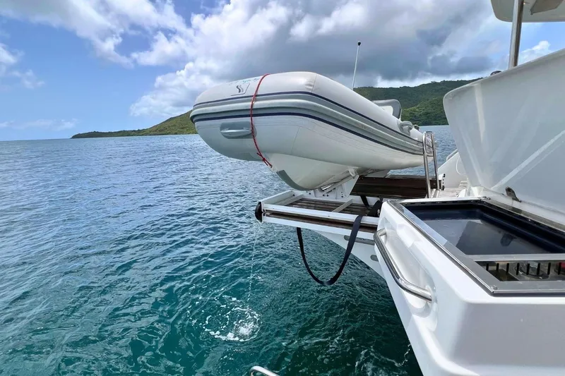 Dignity Yacht Photos Pics Lagoon 50 catamaran with dinghy on davits, 2021 model, anchored in scenic ocean view.